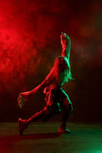 Imagem de mulher de cabelos compridos em jeans dançando danças modernas em fundo vermelho-verde — Fotografia de Stock