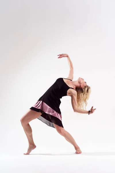 Zdjęcie tańca blond dziewczyna pochylony z wyciągniętą ręką w krótkiej czarnej sukni — Zdjęcie stockowe