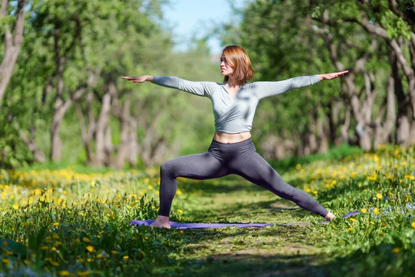 Foto de mujer con las manos a un lado practicando yoga en el bosque —  Fotos de Stock