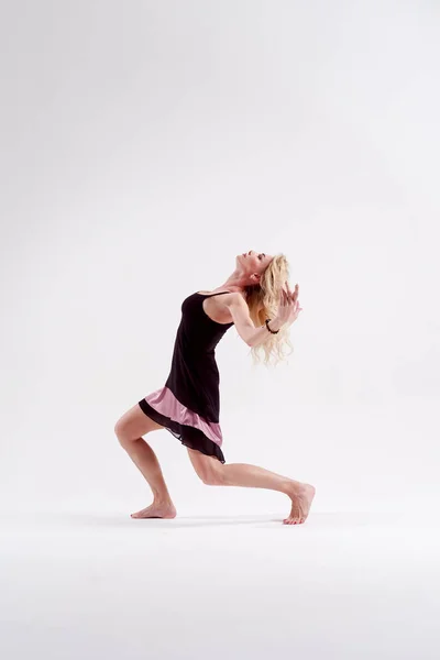 Foto av dansande blondin tittar ner med upphöjda armar i studion — Stockfoto