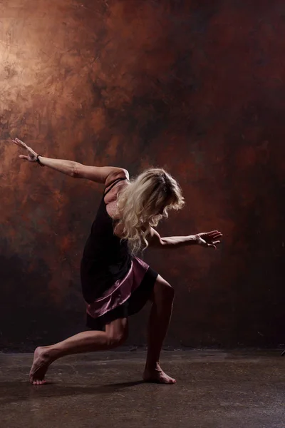 Fullängds foto av ung blond dansare i kort svart klänning på brun bakgrund — Stockfoto