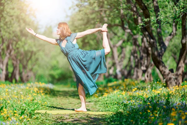 Bild av kvinna i lång grön klänning gör yoga i skogen — Stockfoto