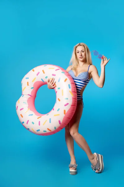 Foto completa de mujer deportiva en traje de baño con bagel inflable sobre fondo azul vacío — Foto de Stock