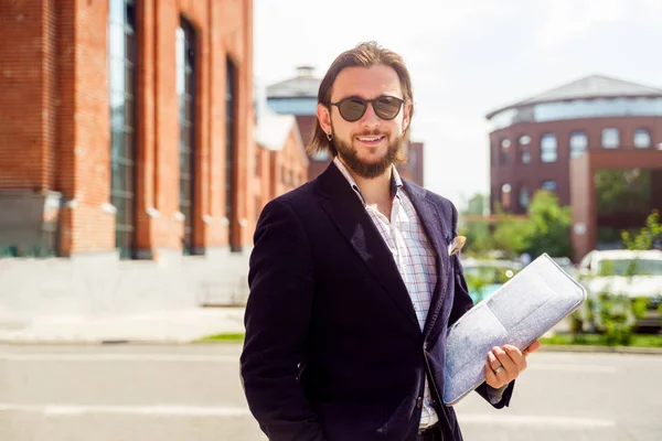 Foto eines glücklichen Mannes in Sonnenbrille und Jacke mit Laptop, der im Frühling in der Stadt steht — Stockfoto