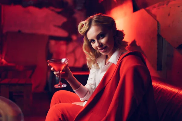 Wizerunek młodej Blondynki w czerwonej kurtce z koktajlem w ręku w klubie nocnym — Zdjęcie stockowe