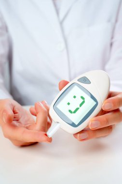 Photo of mans hand with glucometer with cheerful emoticon in studio clipart