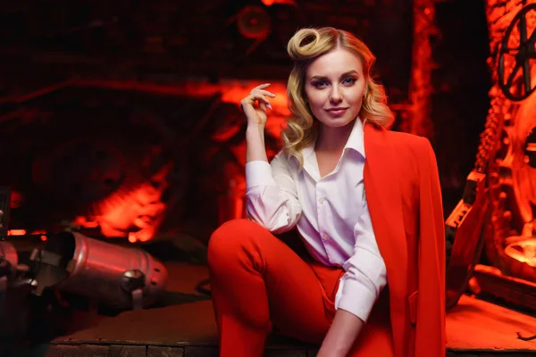 Foto av ung blond flicka i röd jacka tittar på kamera i nattklubb — Stockfoto