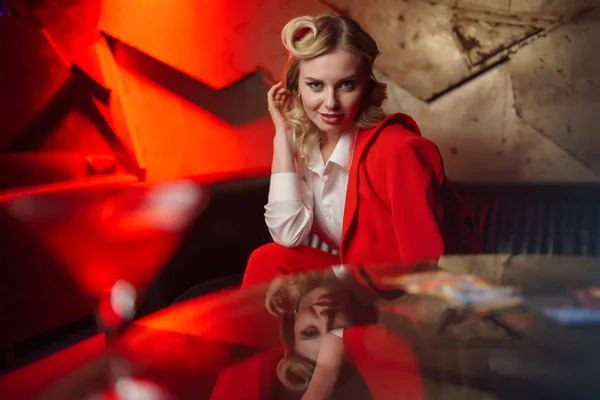 Foto van jonge blonde met krullend haar in rode jas in café — Stockfoto