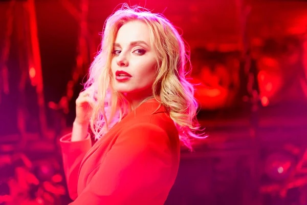 Foto av blondin i röd jacka stående på röd bakgrund — Stockfoto