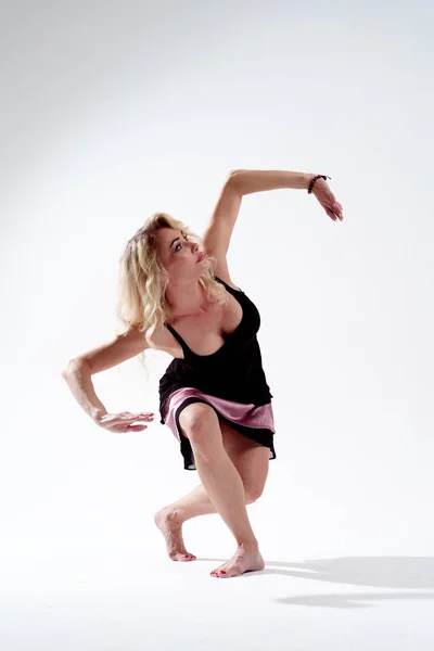 Foto de rubia de pelo largo mirando hacia arriba dedicada a bailar en el estudio sobre fondo blanco vacío — Foto de Stock