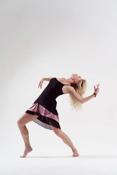Foto av dansande flicka lutar tillbaka med utsträckta arm i kort svart klänning — Stockfoto