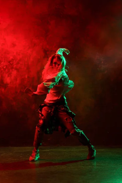 Foto de mulher de cabelos longos em jeans dançando danças modernas em fundo vermelho-verde — Fotografia de Stock