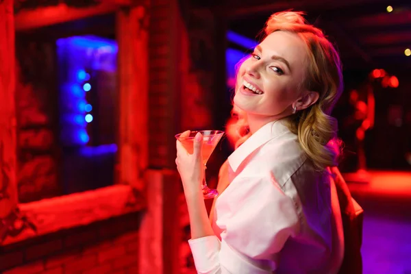 Photo of happy blonde girl with cocktail in her hand at disco — Stock Photo, Image