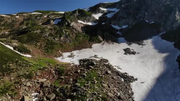 Grandes montagnes grises hautes avec herbe verte et sites enneigés — Video