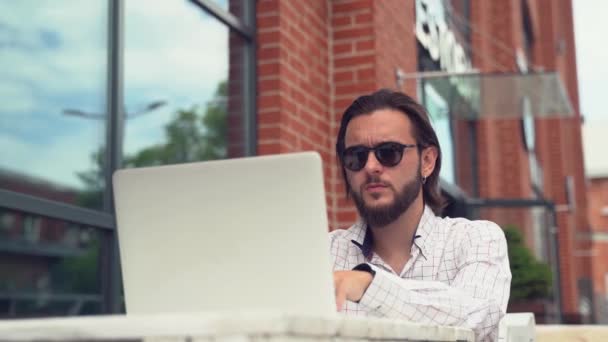 Homem de negócios barbudo elegante em tipos de óculos de sol no laptop — Vídeo de Stock