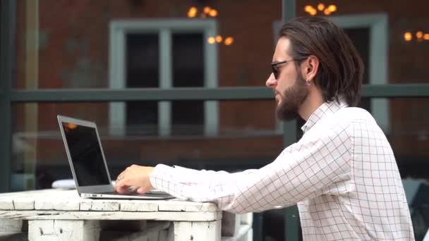 Homme barbu avec des types de boucles d'oreilles sur ordinateur portable dans le restaurant — Video