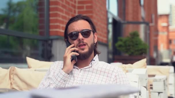 Hombre de negocios guapo con pendiente habla en el teléfono inteligente — Vídeos de Stock