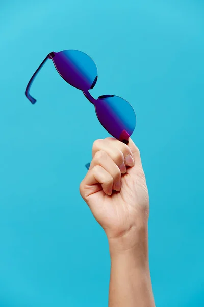 Foto av hand med solglasögon på tom blå bakgrund — Stockfoto