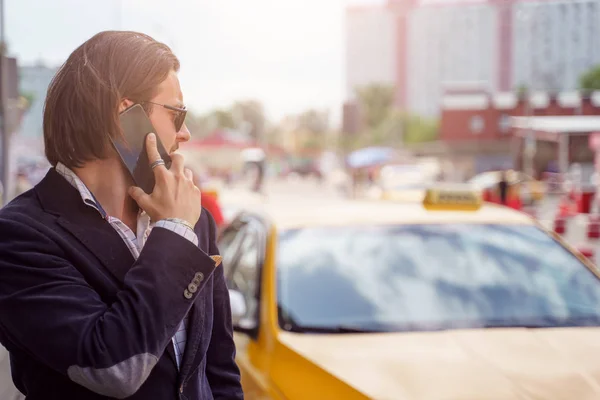 Foto laterale di bruna che parla al telefono vicino all'auto gialla in città — Foto Stock