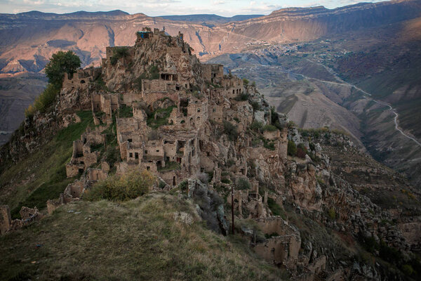 Фото древних руин, горной местности с зеленой растительностью на фоне облачного голубого неба
