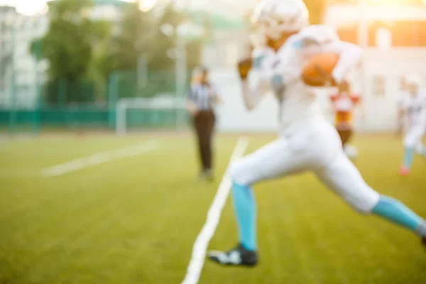 Foto eines jungen Athleten, der im Sommer auf der grünen Wiese American Football spielt — Stockfoto