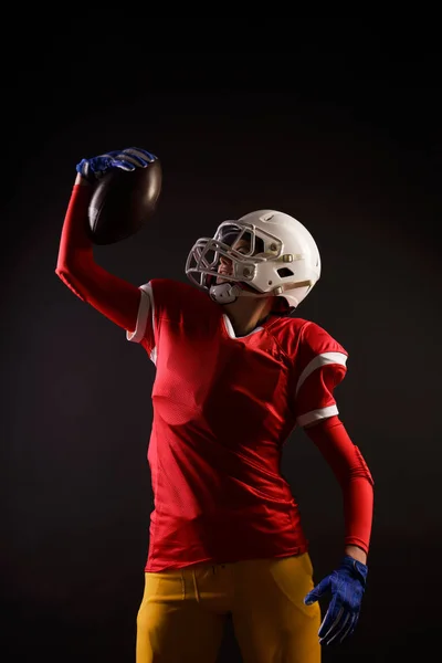 Photo of american female football player in helmet with ball raised up