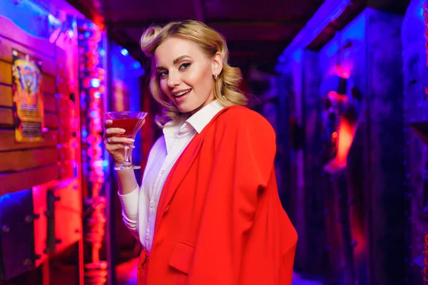 Photo of blonde woman with cocktail in her hand on red and blue background — Stock Photo, Image