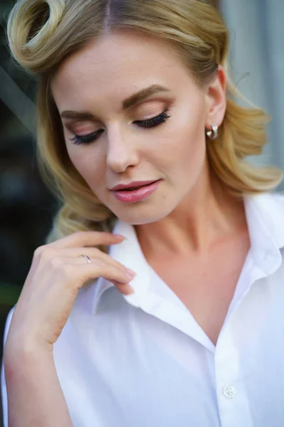 Portrait of young blonde with closed eyes in white shirt on street — Stock Photo, Image