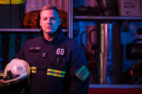 Το χαρακτηριστικό του πυροσβέστη κοιτάζοντας την κάμερα κοντά πυροσβεστικό όχημα — Φωτογραφία Αρχείου