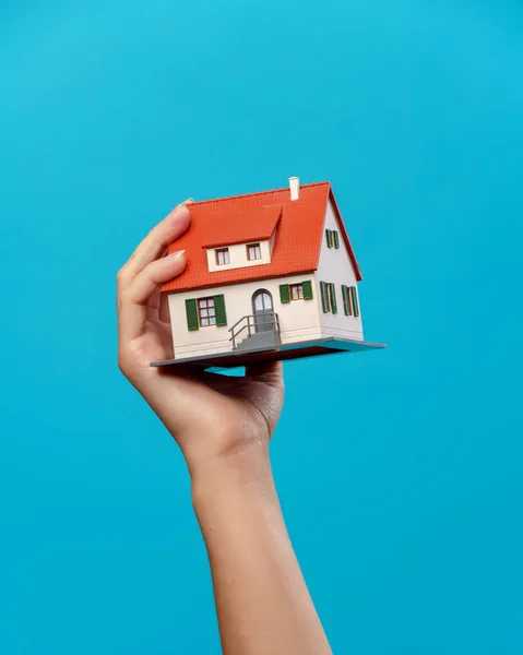 Immagine di mani con casa su sfondo blu vuoto — Foto Stock