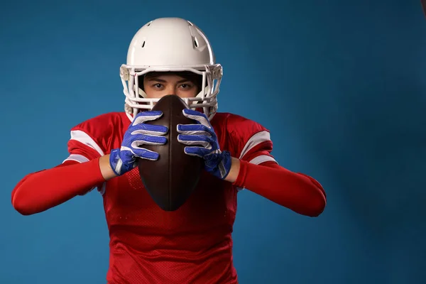 Picture of american girl football player in white helmet, sportswear and ball in her hands