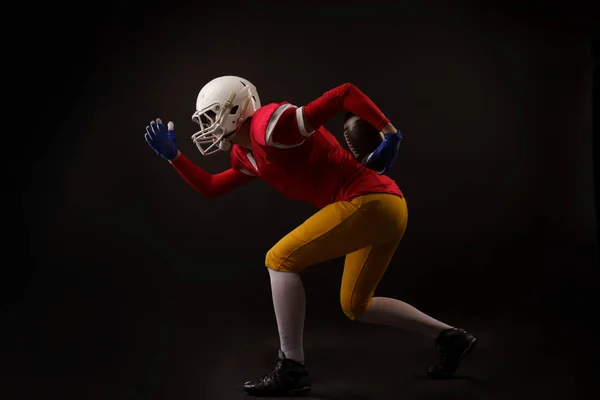 Fotografie strany běžící ženský fotbalový hráč na helmici ve studiu — Stock fotografie