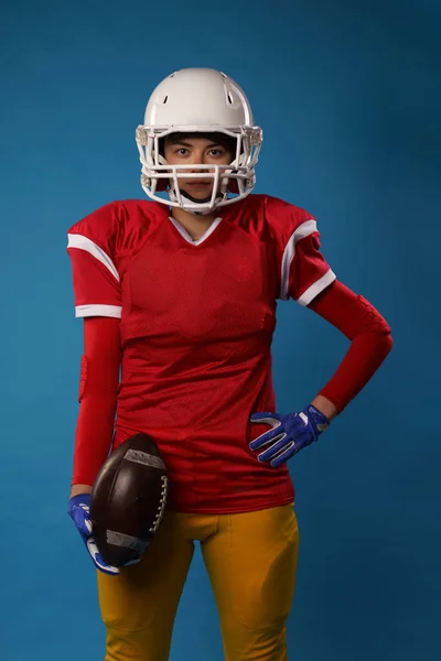 Fotó fiatal amerikai nő focista, fehér sisak, sportruházat a labdát a kezében — Stock Fotó