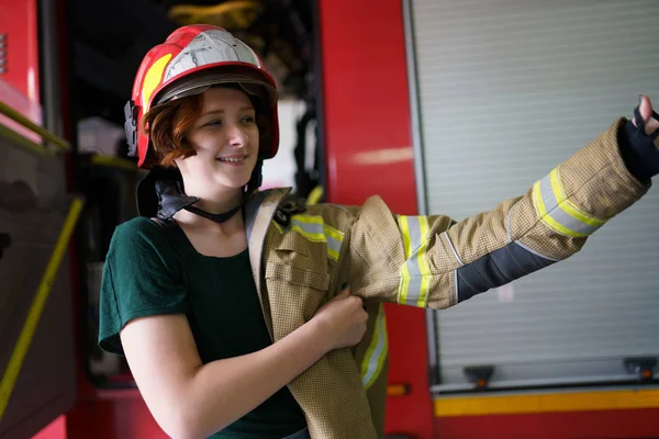 Foto einer Frau mit Helm, die Arbeitskleidung im Feuerwehrauto anzieht — Stockfoto