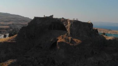 güneş ışığı ile aydınlatılmış kahverengi kayalık uçurumun üzerinde kale silueti