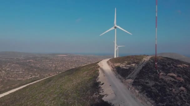 Molinos de viento de trabajo conectados por carretera terrestre marrón en la costa — Vídeo de stock
