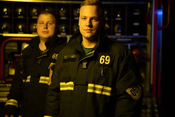 Fotka dvou hasičů, kteří se dívají do kamery poblíž hasičového vozu, — Stock fotografie
