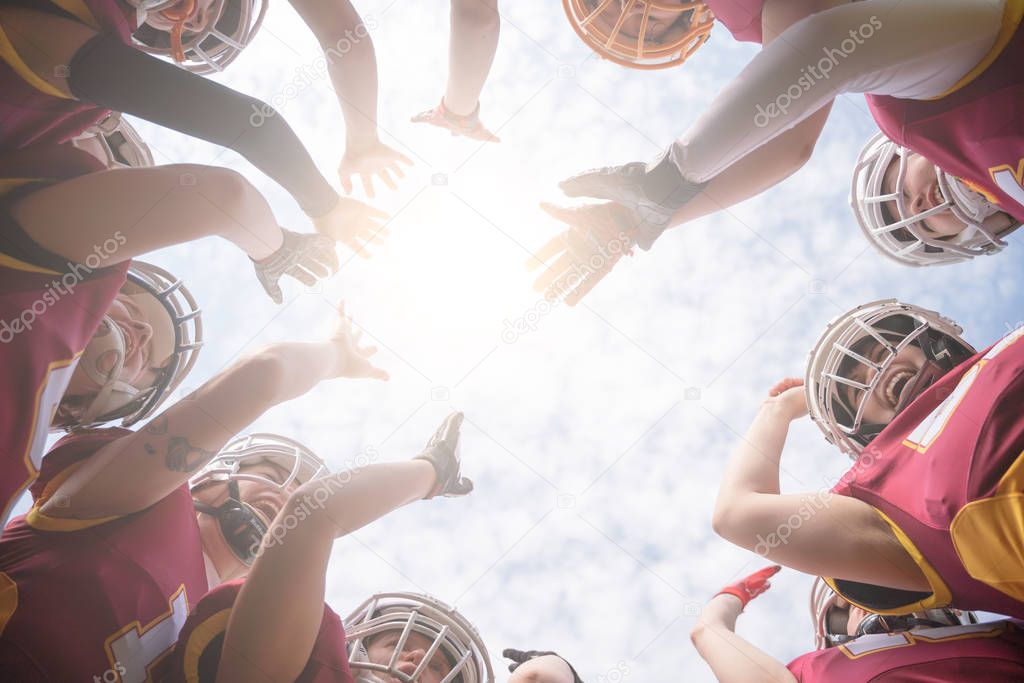 Image from below of team of American football players against blue sky