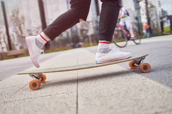 Bild von Beinen einer Frau in schwarzen Jeans, die auf der Straße in der Stadt Skateboard fährt — Stockfoto