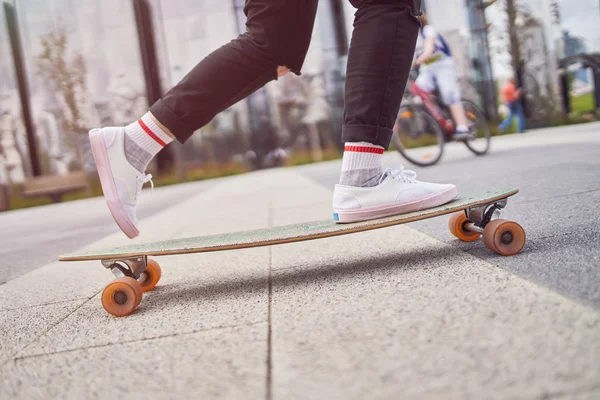 Obrázek nohou ženy v černých džínách jezdila na skateboard na ulici ve městě — Stock fotografie