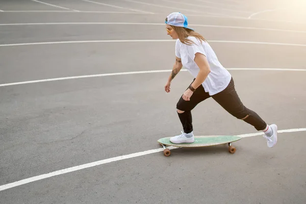 Foto einer brünetten Frau mit Baseballkappe beim Skateboardfahren im Freien — Stockfoto