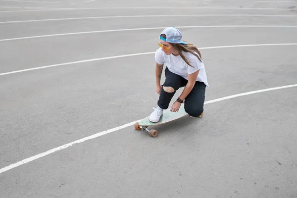 Foto auf der Seite einer brünetten Frau mit Baseballkappe beim Skateboardfahren im Freien — Stockfoto