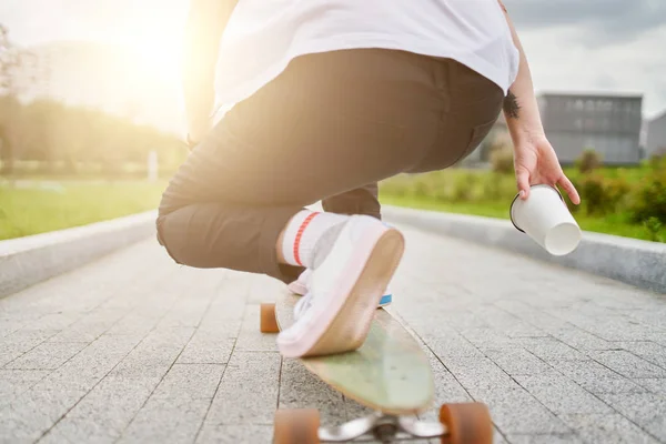 Foto van Womans benen in witte sneakers rijden skateboard op straat in de stad op de zomerdag. — Stockfoto
