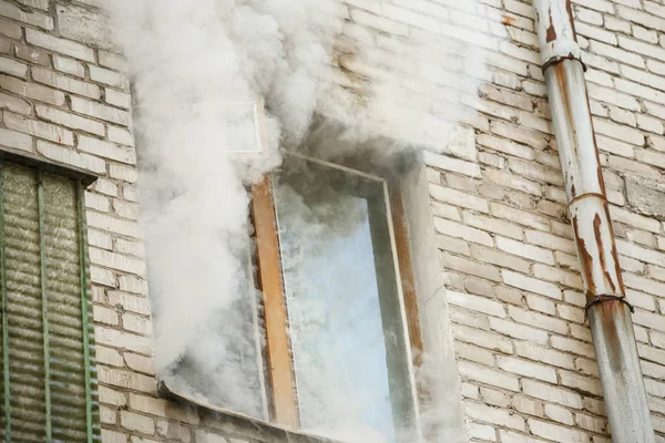 Image of brick house with smoke coming out of window — Stock Photo, Image