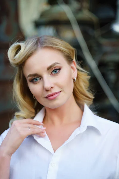 Photo of young blonde in white shirt looking at camera on street, blurred background — Stock Photo, Image