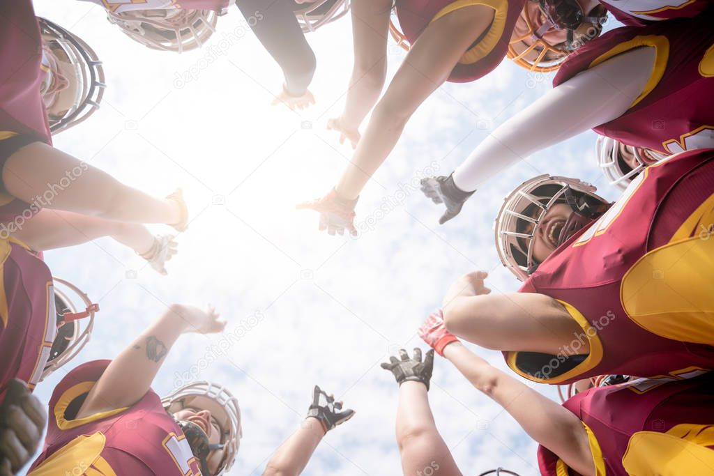 Photo from below of team of American football players against blue sky