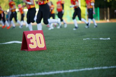 Photo of soccer field with number thirty running football players on blurred background clipart