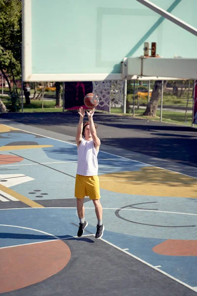 Полная фотография спортсмена, бросающего мяч в баскетбольное кольцо на детской площадке . — стоковое фото