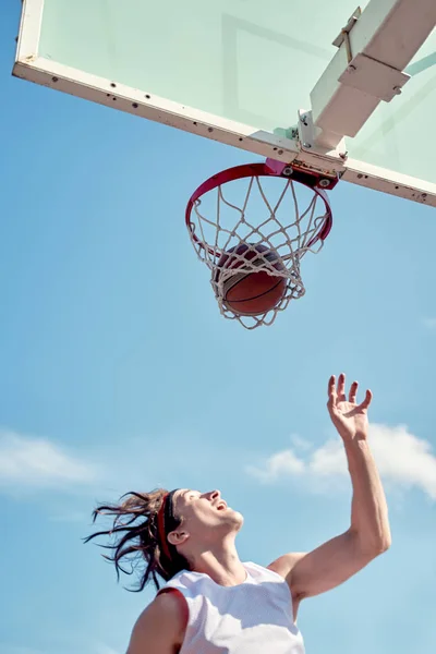 Фото спортсмена, бросающего мяч в баскетбольное кольцо на спортивной площадке на улице в летний день . — стоковое фото