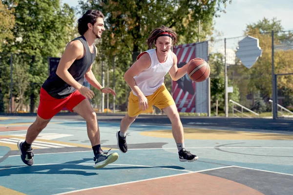 Фото двух спортсменов, играющих в баскетбол на детской площадке в летний день . — стоковое фото